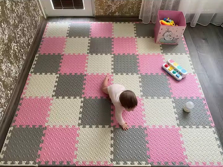 Child playing on an interlocking foam mat with toys scattered around.